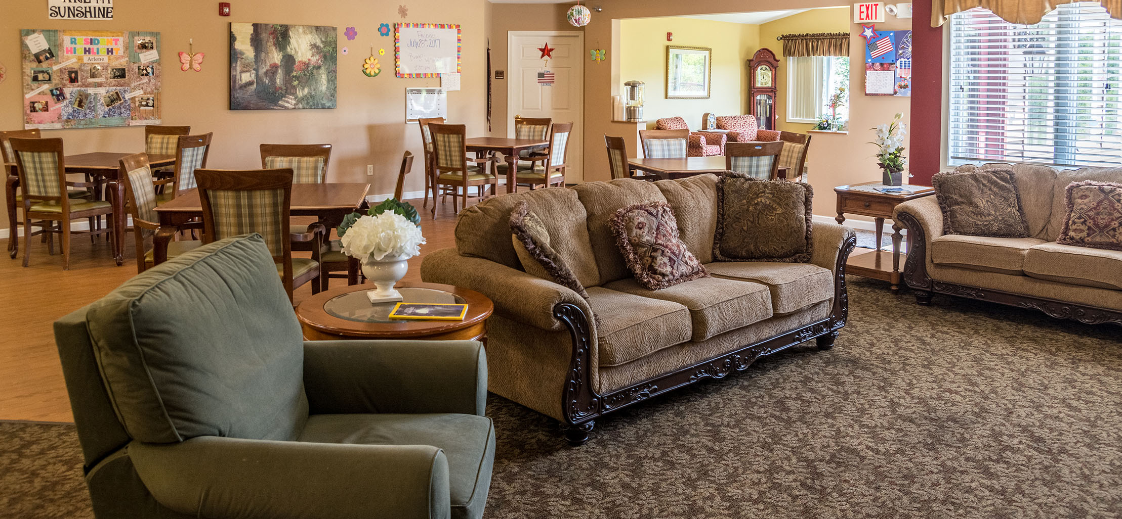 living room space with bulletin board and a green chair - New Perspective Careers Assisted Living Careers